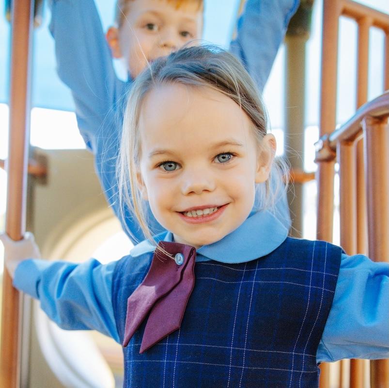 Close up of a smiling student on a playground, who is well known and nurtured by the community at Medowie Christian College.