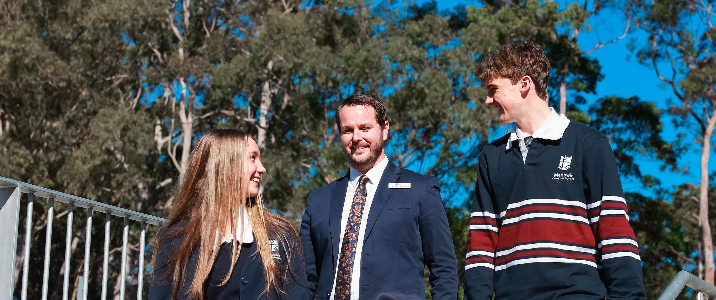 Medowie School Pricipal Dan Weeks walking and talking with school captains under tall eucalyptus trees