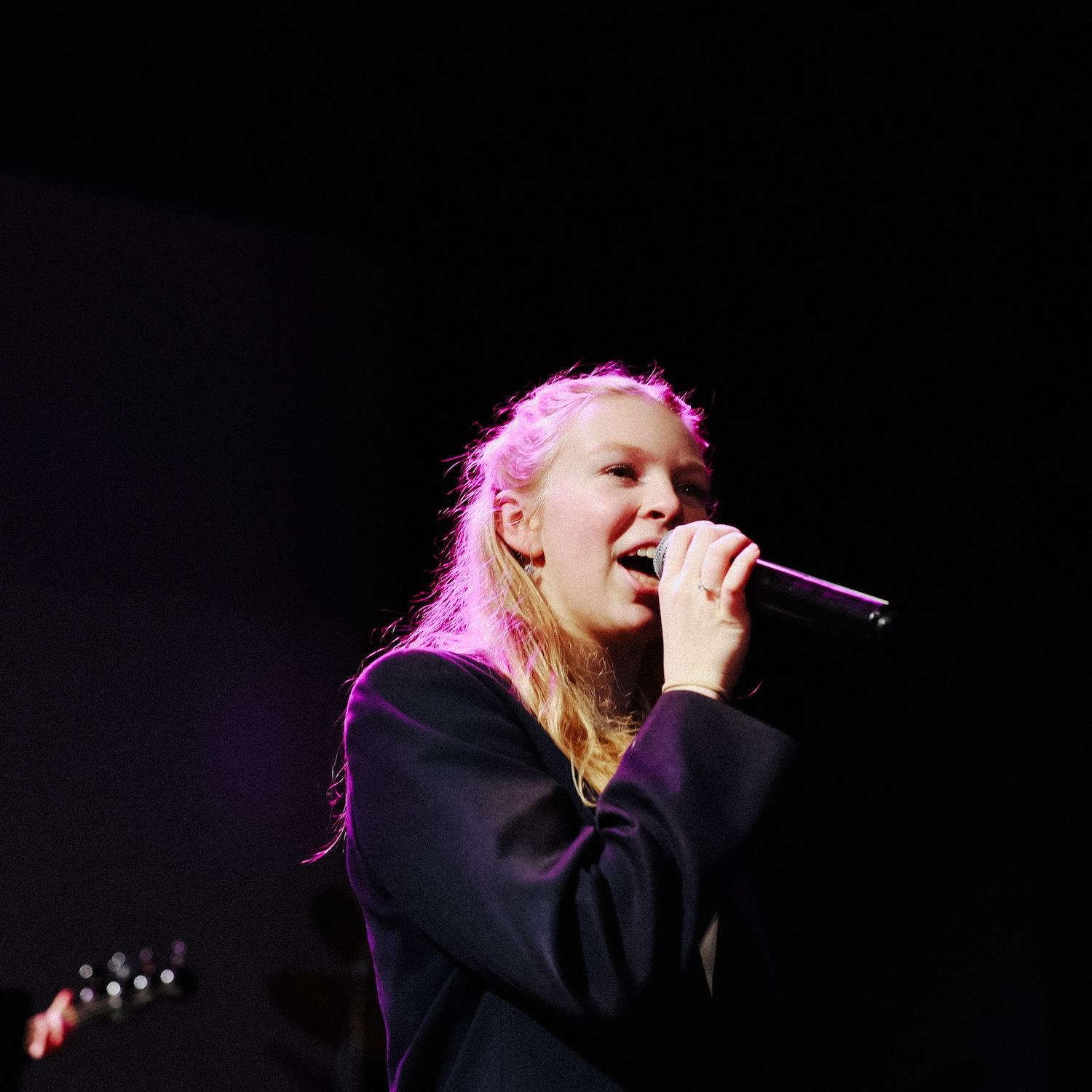 Secondary school girl singing on stage with backlight showcasing talent and confidence