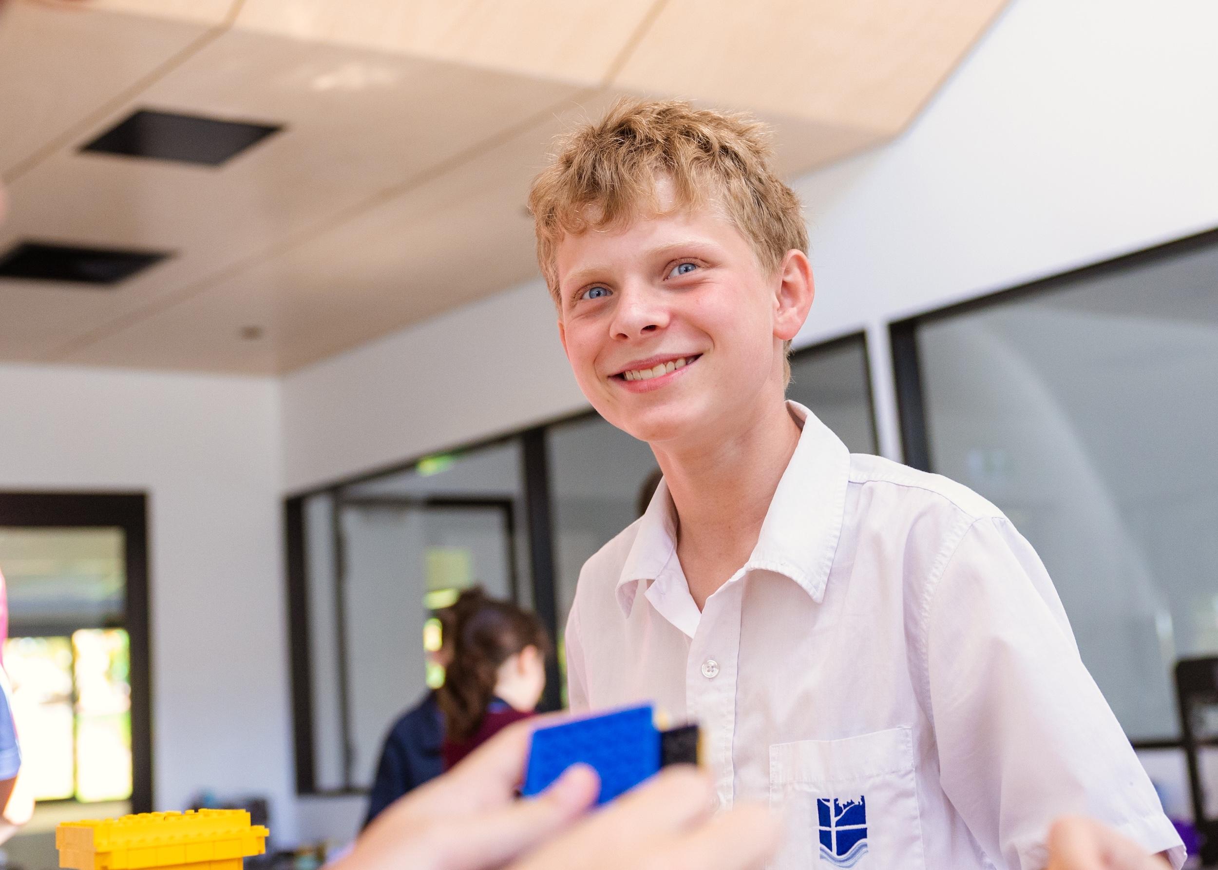 A student at Medowie Christian School smiling during a classroom activity, highlighting the welcoming community.