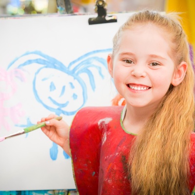 Outside of School Hours Care girl smiling in front of painting