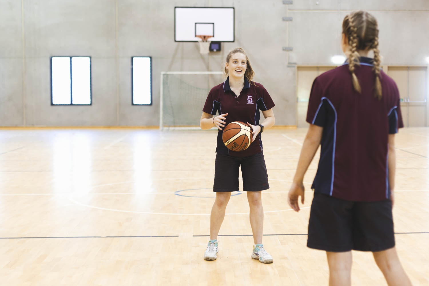 female secondary school student in sports uniform about to pass basketball