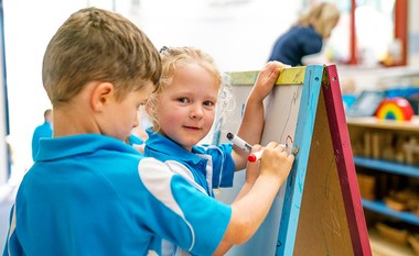 Prep school student drawing on whiteboard easel