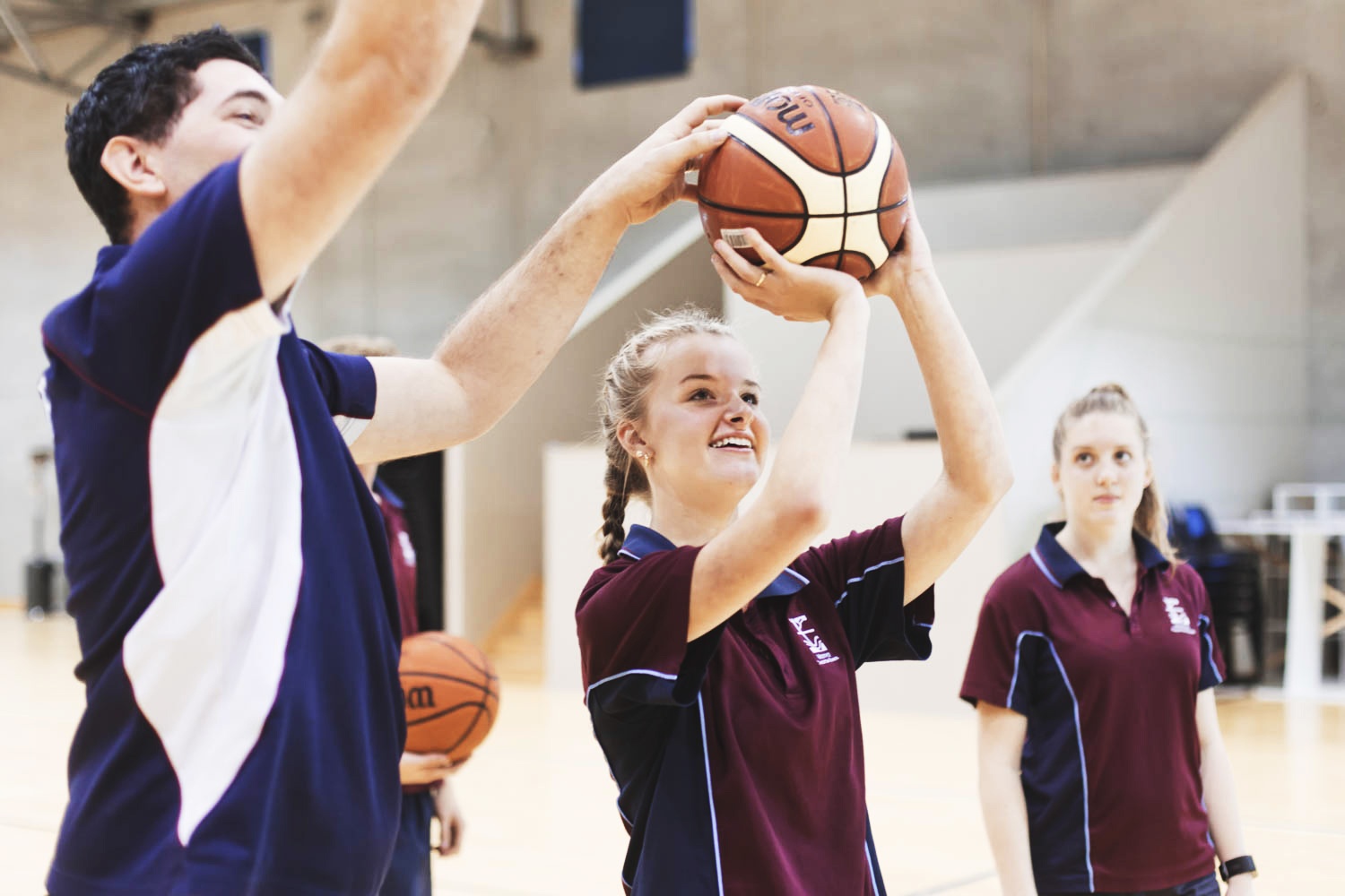 Teacher teaching female student in Medowie sports uniform how to shoot basketball