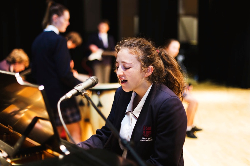 female secondary student singing and playing piano on Medowie school stage