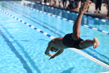 boy diving into swimming pool at start of race