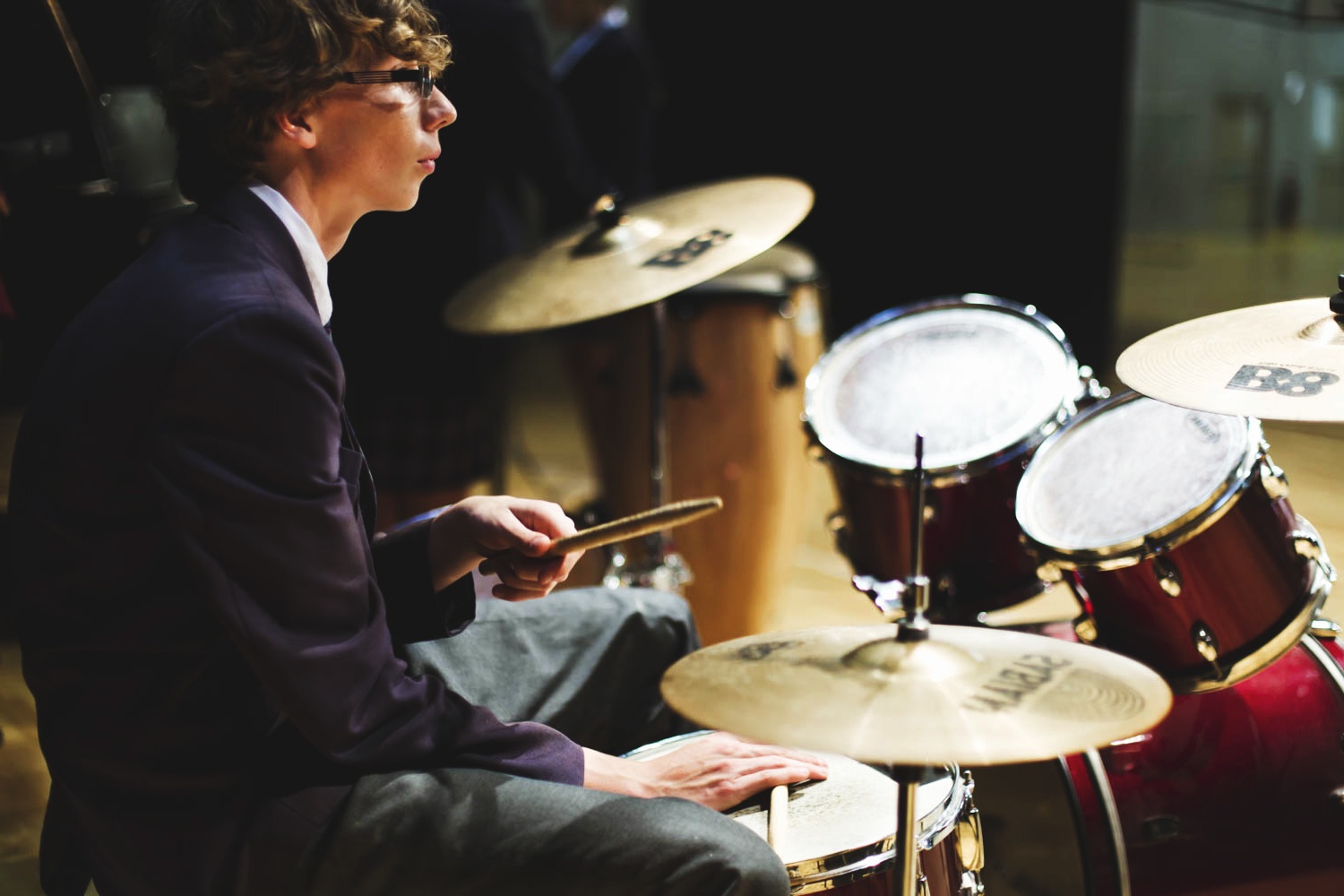 side view of male student sitting at drum kit